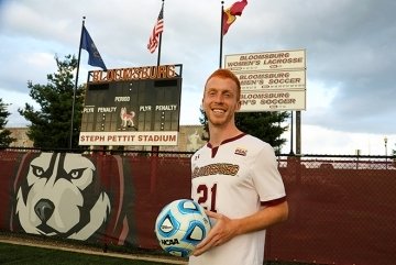 A guy holding a soccer ball on a soccer field. 