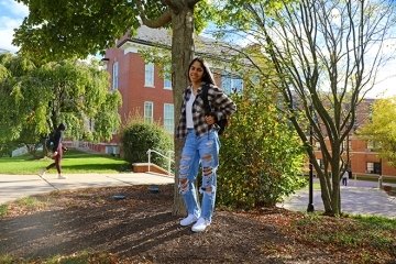 A girl standing by a tree. 