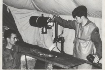 A black and white photo of two guys working together. 