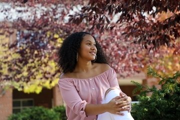 A woman sitting by some trees. 