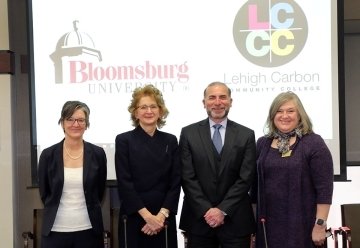 Four people standing in front of a smart board.