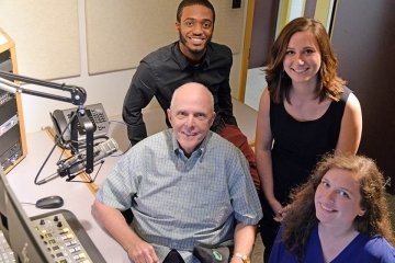 A group of four sitting in a studio.