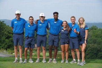 A group standing side by side. They are all wearing blue. 