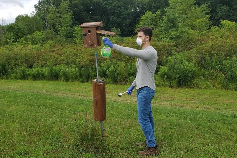 A guy standing by a bird feeder. 