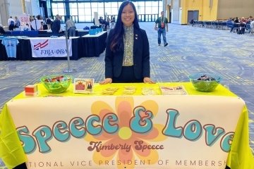 A girl standing behind a table. 