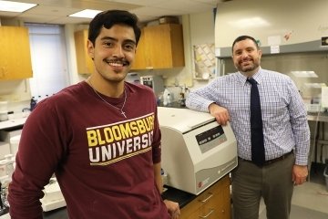 A guy in a Bloomsburg University shirt in a science lab. 