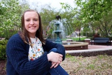 A girl sitting by a fountain.