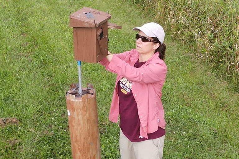 A woman filling a bird feeder. 