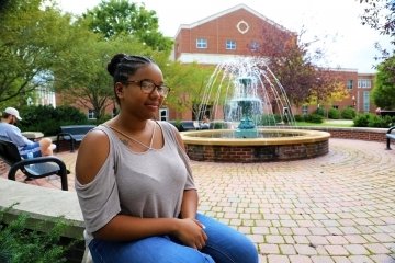 A girl sitting by a fountain. 