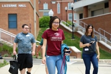 Three people walking in front of a school.