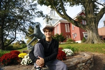 Randy Sea sitting on the ledge of a flower bed, with one leg bent up close to him. 