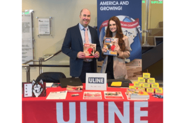 Two people standing behind a vendor table that says ULINE