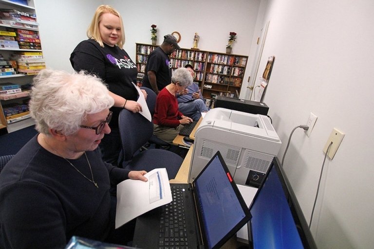 Two people working together, looking at a computer. 