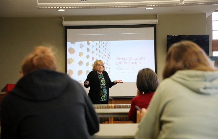 A group looking at a presentation and the presenter. 