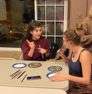 Two girls sitting at a table painting. 