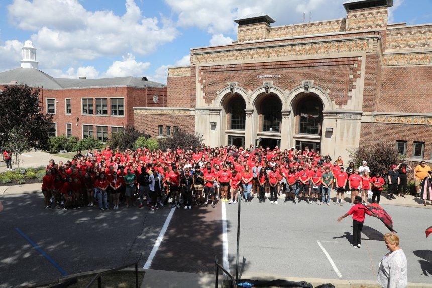 The outside of Straughn Auditorium at CU-Mansfield with the band standing in front of it. 