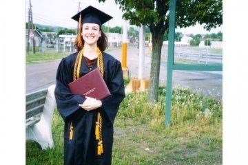 A woman in a cap and gown standing outside. 