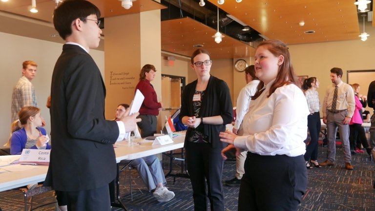 Two people talking to each other in front of a table. 