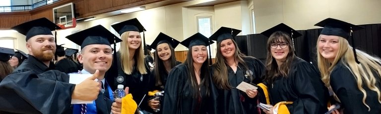 A group of students in their caps and gowns taking a selfie together. 