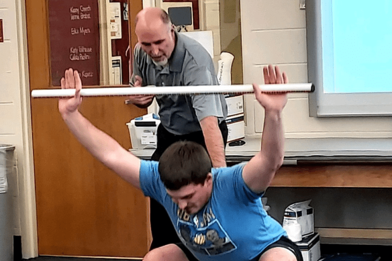 A man squatting with a bar. 