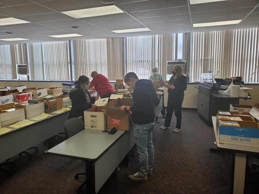 A group of people at tables with boxes. 