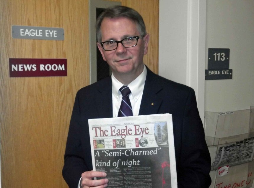 A man standing with a newspaper. 