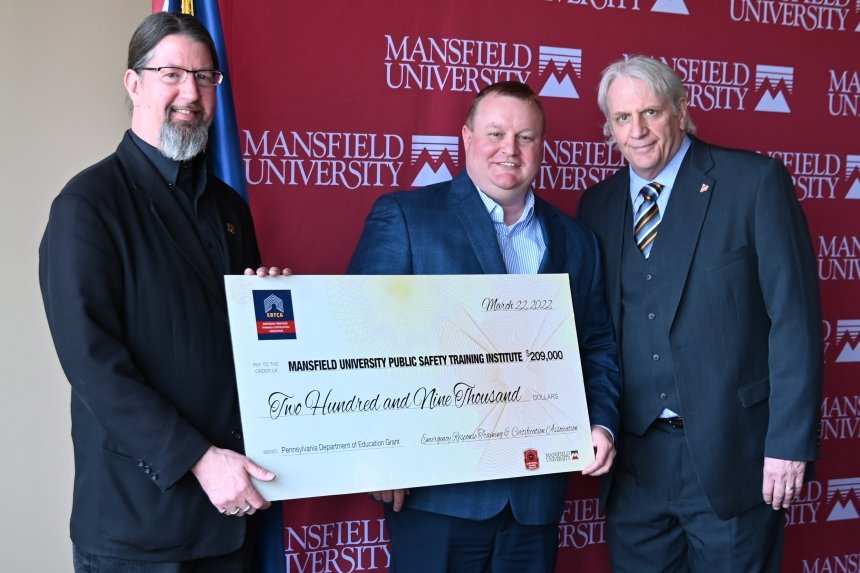 A group of people standing with a large check. 