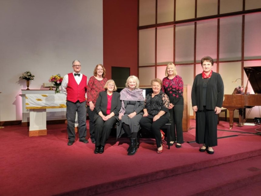 A group of people standing and sitting on stage. 