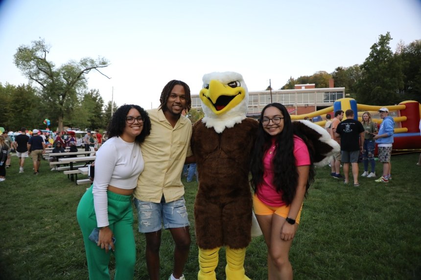 A group of people standing together with an eagle mascot. 