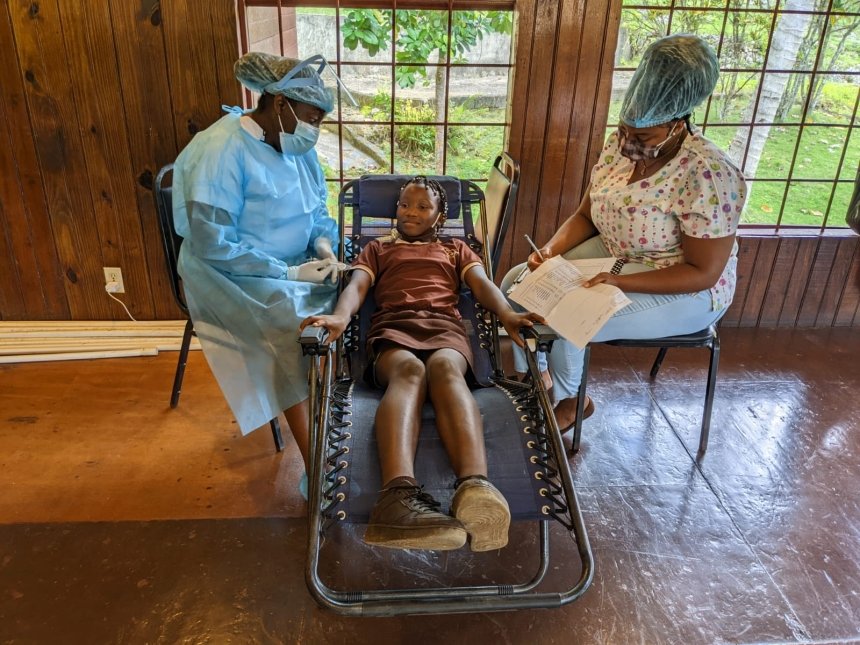 A kid sitting in a chair with two doctors. 