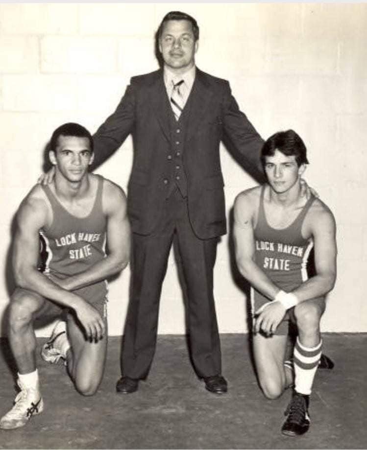 Two wrestlers crouching next to a coach. 