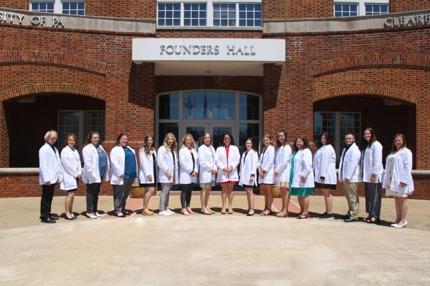 A group of nurses standing side by side in front of a building. 