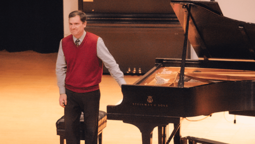 A man standing near a piano. 