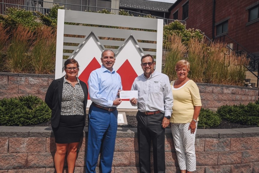 A group of people standing with a check. 