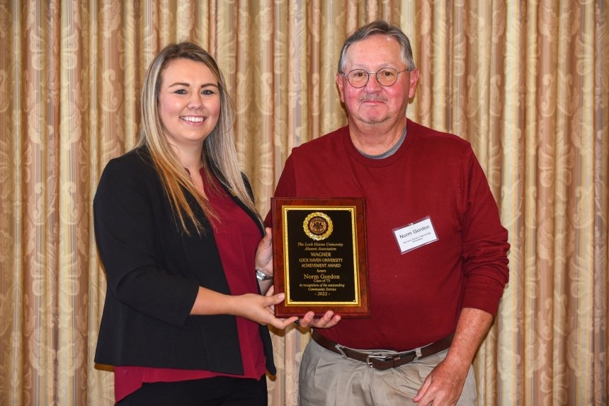 Two people standing with an award. 