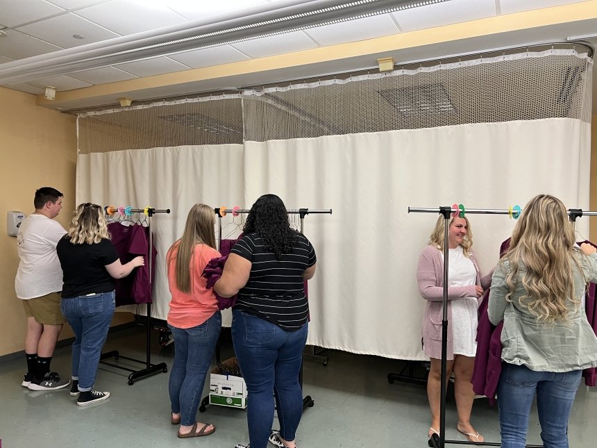 A group looking at scrubs on a rack. 