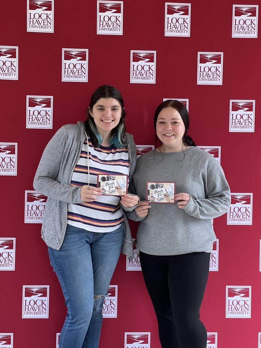 Two girls standing side by side holding thank you cards. 