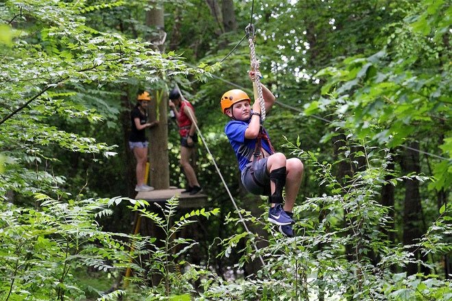 Person riding zip line on high ropes course at CU-Bloomsburg